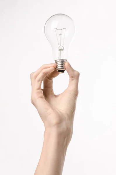 Consumo de energía y ahorro de energía: mano humana sosteniendo una bombilla sobre un fondo blanco en estudio — Foto de Stock