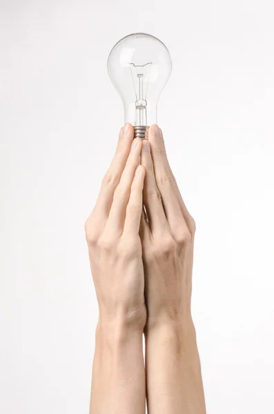 Energi och energibesparing ämne: mänskliga handen håller en glödlampa på en vit bakgrund i studio — Stockfoto
