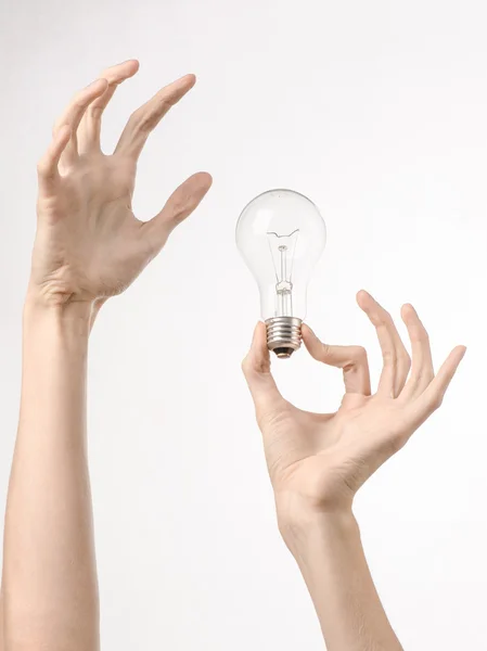 Energy consumption and energy saving topic: human hand holding a light bulb on a white background in studio — Stock Photo, Image