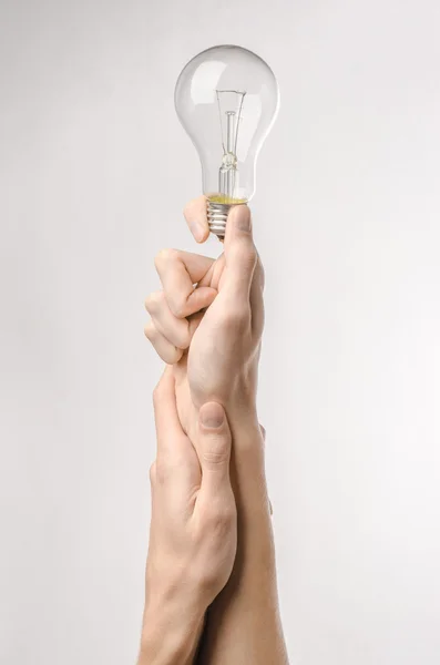 Consumo di energia e risparmio energetico argomento: mano umana tenendo una lampadina su sfondo bianco in studio — Foto Stock