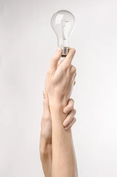 Energieverbruik en energiebesparing onderwerp: menselijke hand met een lampje op een witte achtergrond in studio — Stockfoto