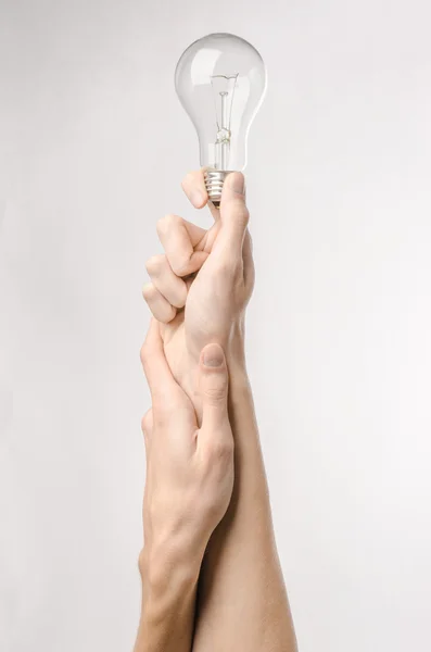 Consumo di energia e risparmio energetico argomento: mano umana tenendo una lampadina su sfondo bianco in studio — Foto Stock