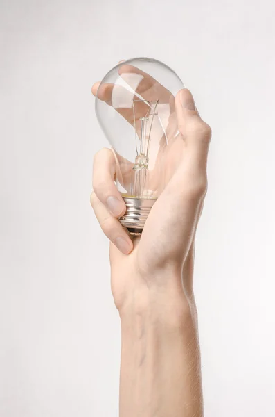 Consumo de energia e tópico de economia de energia: mão humana segurando uma lâmpada em um fundo branco no estúdio — Fotografia de Stock