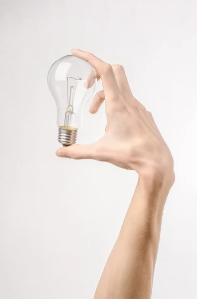 Consumo di energia e risparmio energetico argomento: mano umana tenendo una lampadina su sfondo bianco in studio — Foto Stock