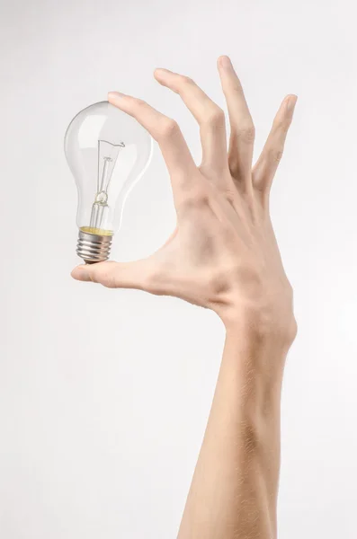 Consumo di energia e risparmio energetico argomento: mano umana tenendo una lampadina su sfondo bianco in studio — Foto Stock