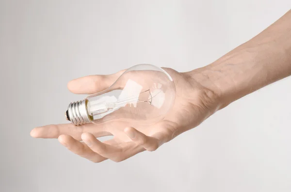 Energieverbruik en energiebesparing onderwerp: menselijke hand met een lampje op een witte achtergrond in studio — Stockfoto