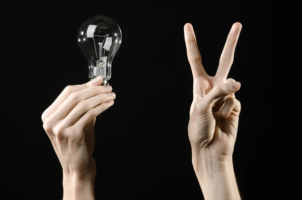 Energy consumption and energy saving topic: human hand holding a light bulb on black background in studio — Stock Photo, Image