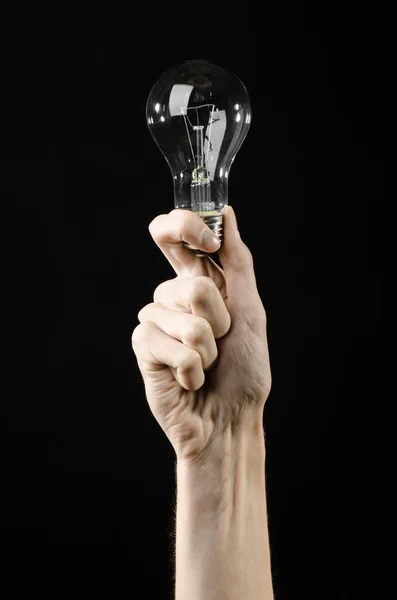 Energy consumption and energy saving topic: human hand holding a light bulb on black background in studio — Stock Photo, Image