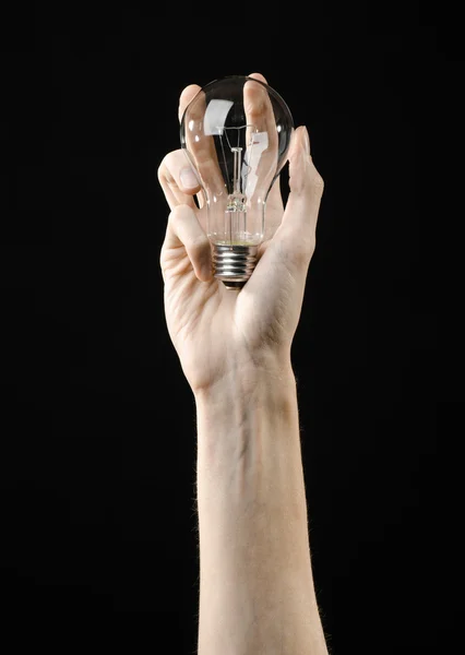 Consumo de energía y ahorro de energía: mano humana sosteniendo una bombilla sobre fondo negro en el estudio — Foto de Stock