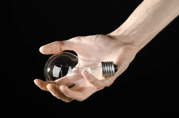 Spotřeba energie a energeticky úsporných téma: lidská ruka držící žárovky na černém pozadí v studio — Stock fotografie