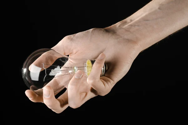 Consommation d'énergie et économie d'énergie thème : main humaine tenant une ampoule sur fond noir en studio — Photo
