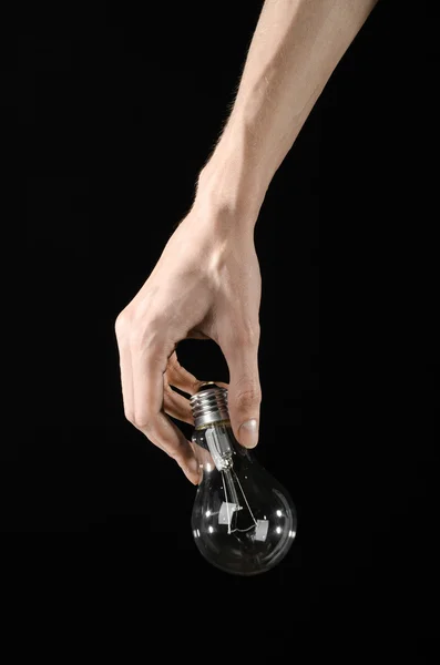 Energy consumption and energy saving topic: human hand holding a light bulb on black background in studio — Stock Photo, Image