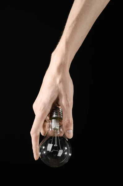 Energy consumption and energy saving topic: human hand holding a light bulb on black background in studio — Stock Photo, Image