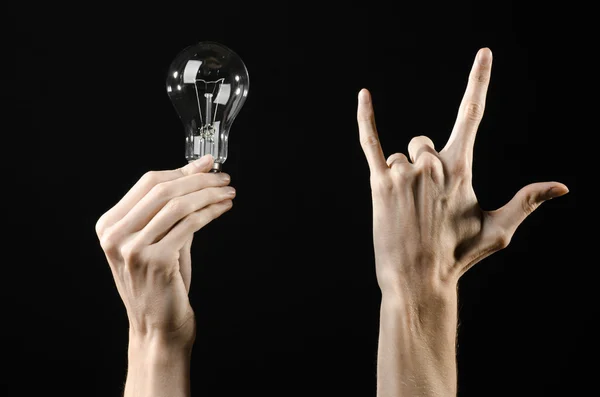 Energieverbruik en energiebesparing onderwerp: menselijke hand met een gloeilamp op zwarte achtergrond in studio — Stockfoto