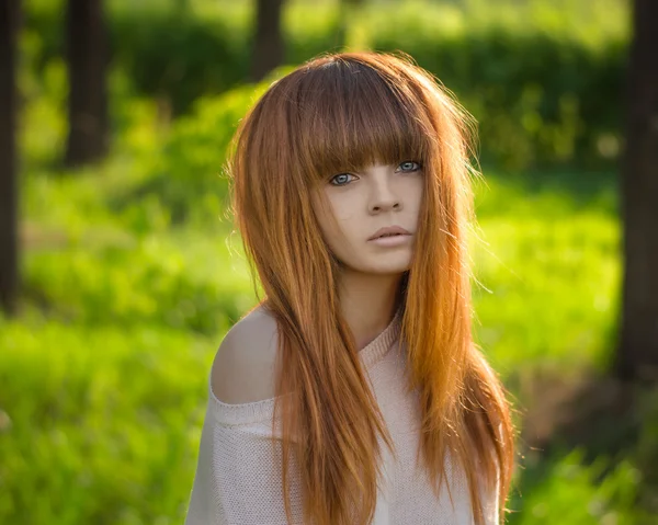 Menina com cabelo vermelho, menina de cabelos vermelhos de pé na floresta e o sol brilha — Fotografia de Stock