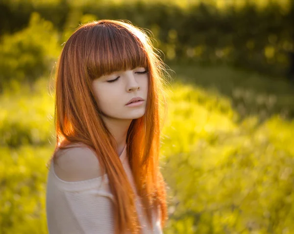 Menina com cabelo vermelho, menina de cabelos vermelhos de pé na floresta e o sol brilha — Fotografia de Stock