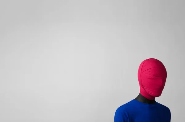 Surrealism Theme: man in a blue jacket with a pink cloth tied around his head is in the corner on a gray background — Stock Photo, Image