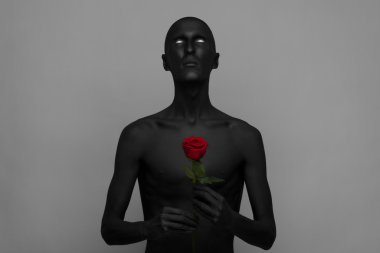 Gotik ve Halloween Tema: siyah deri bir kırmızı gül, kara ölüm Studio gri bir arka plan üzerinde izole tutan bir adam