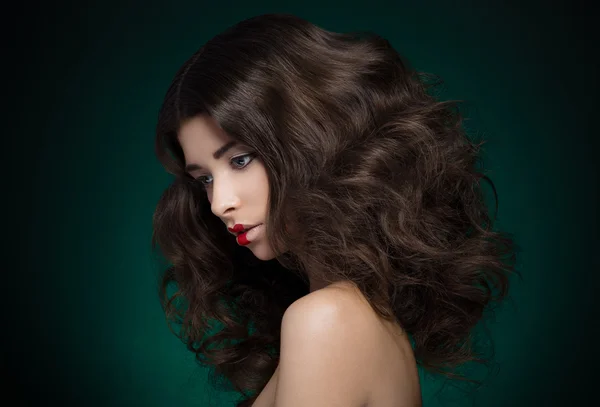Cabello y maquillaje tema: un modelo de chica muy hermosa con pelo exuberante y maquillaje creativo sobre fondo azul-verde — Foto de Stock