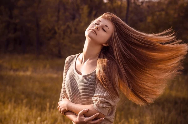Dramatisches Porträt eines Mädchenthemas: Porträt eines schönen Mädchens mit fliegendem Haar im Wind vor einem Hintergrund im Wald — Stockfoto