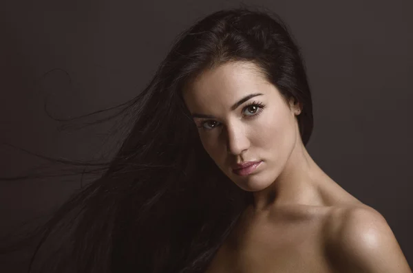 Dramatic portrait of a girl theme: portrait of a beautiful girl with flying hair in the wind against a background in the studio — Stock Photo, Image