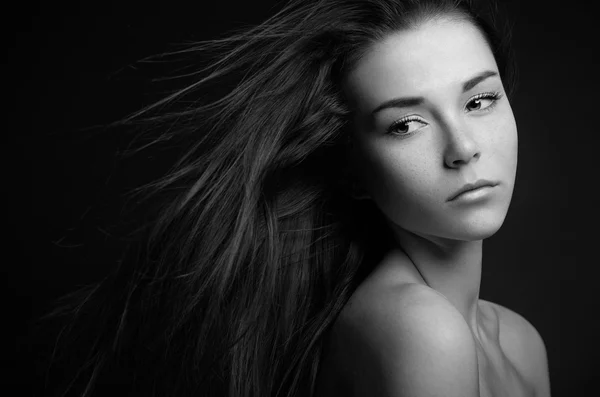 Dramatic portrait of a girl theme: portrait of a beautiful lonely girl with flying hair in the wind isolated on dark background in studio — Stock Photo, Image