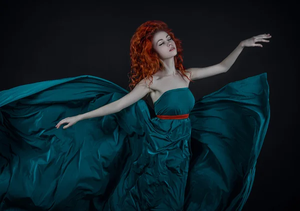 Chica en un vestido de seda, una hermosa chica pelirroja bailando en un vestido verde largo volando en el aire, un vestido verde largo —  Fotos de Stock