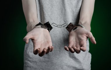 Hapishane ve hüküm giymiş Konu: adam elinde bir gri T-shirt üzerinde kelepçe ve koyu yeşil bir arka plan üzerinde uyuşturucu satıcısı kelepçe koymak Studio, üzerinde kot