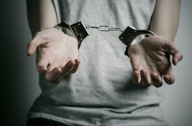 Hapishane ve hüküm giymiş Konu: adam elinde kelepçe tecavüzcü koymak Studio, gri bir arka plan üzerinde gri bir T-shirt üzerinde kelepçe ile