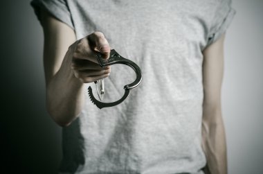 Hapishane ve hüküm giymiş Konu: adam elinde kelepçe tecavüzcü koymak Studio, gri bir arka plan üzerinde gri bir T-shirt üzerinde kelepçe ile