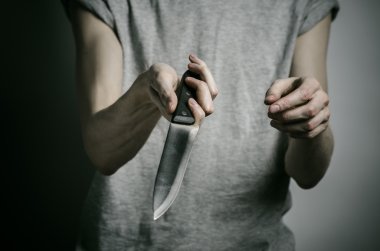 Cinayet ve Halloween Tema: gri bir arka plan üzerinde elinde bir bıçakla bir adam