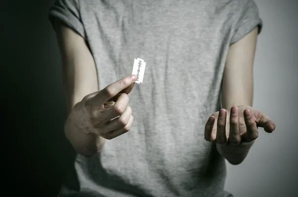 Depressie en zelfmoord thema: man met een scheermes aan zelfmoord op een grijze achtergrond in de studio — Stockfoto