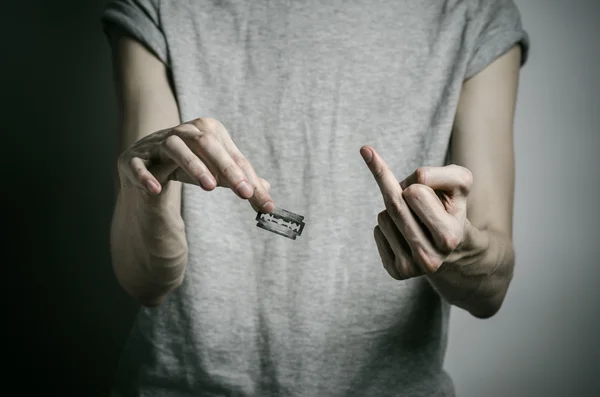 Депресія і тема самогубства: чоловік тримає бритву для самогубства на сірому фоні в студії — стокове фото