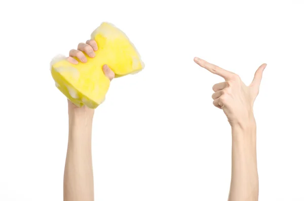 Rengöring i avsnittet hus och sanitet: handen håller en gul svamp våt med skum isolerad på en vit bakgrund i studio — Stockfoto