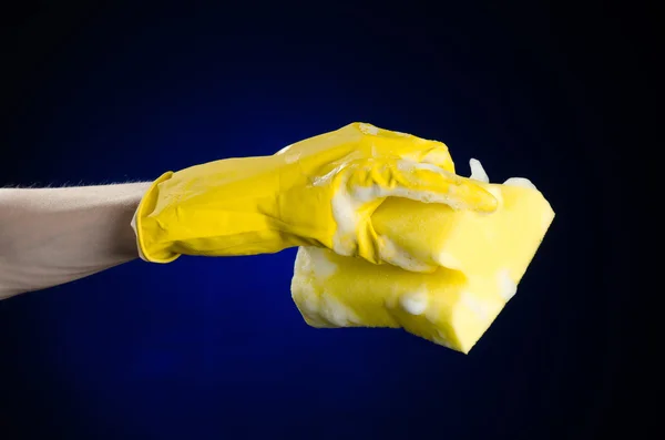 Nettoyage de la maison et assainissement thème : Main tenant une éponge jaune mouillée avec de la mousse sur un fond bleu foncé en studio — Photo