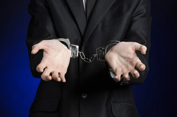 Korupce a úplatkářství téma: podnikatel v černém obleku s pouty na rukou na tmavě modrém pozadí ve studiu izolovaných — Stock fotografie