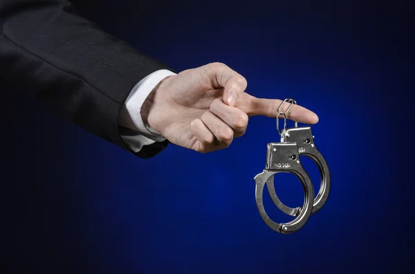 Corruption and bribery theme: businessman in a black suit with handcuffs on his hands on a dark blue background in studio isolated — Stock Photo, Image