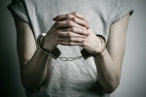Gefängnis und verurteiltes Thema: Mann mit Handschellen an den Händen in grauem T-Shirt vor grauem Hintergrund im Studio, legt Vergewaltiger Handschellen an — Stockfoto