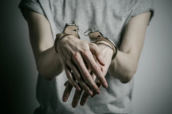 监狱和被定罪的主题: 人与灰色的 t 恤在工作室里，铐上强奸犯的灰色背景在他手上的手铐 — 图库照片