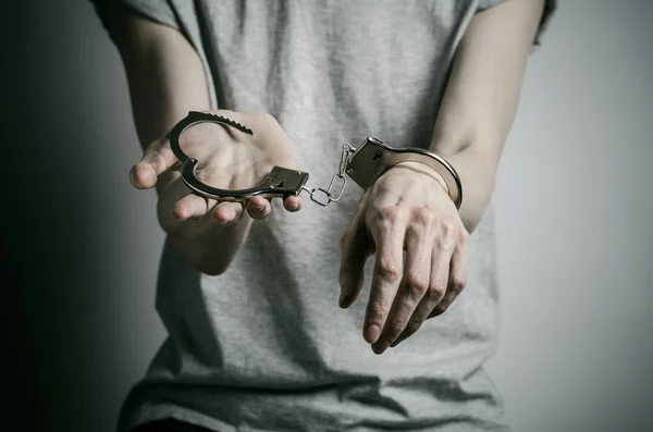 Gefängnis und verurteiltes Thema: Mann mit Handschellen an den Händen in grauem T-Shirt vor grauem Hintergrund im Studio, legt Vergewaltiger Handschellen an — Stockfoto