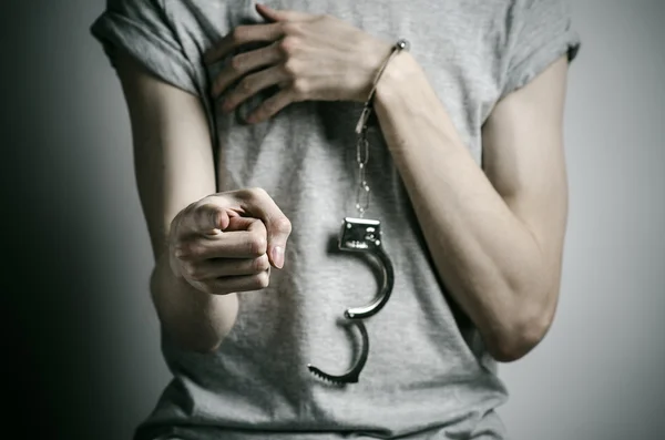 Gefängnis und verurteiltes Thema: Mann mit Handschellen an den Händen in grauem T-Shirt vor grauem Hintergrund im Studio, legt Vergewaltiger Handschellen an — Stockfoto