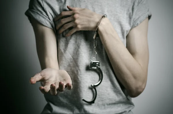 监狱和被定罪的主题: 人与灰色的 t 恤在工作室里，铐上强奸犯的灰色背景在他手上的手铐 — 图库照片