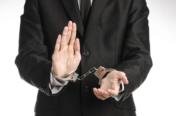 Коррупция и взяточничество тема: бизнесмен в черном костюме с наручниками на руках на белом фоне в изолированной студии — стоковое фото