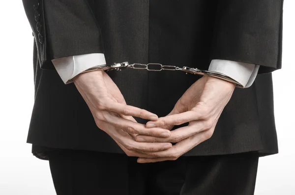 Коррупция и взяточничество тема: бизнесмен в черном костюме с наручниками на руках на белом фоне в изолированной студии — стоковое фото