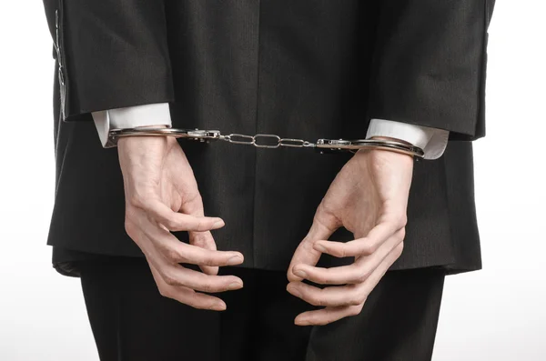 Corruption and bribery theme: businessman in a black suit with handcuffs on his hands on a white background in studio isolated — Stock Photo, Image