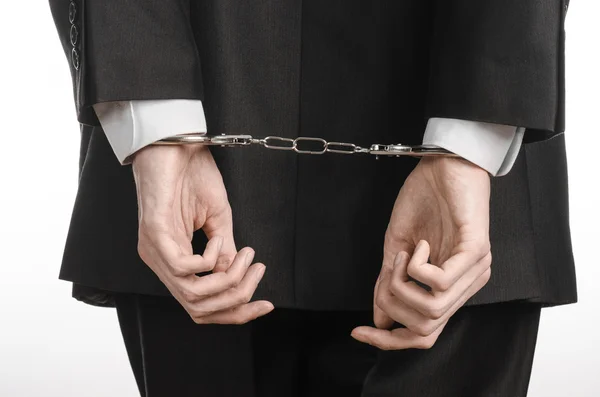 Corruption and bribery theme: businessman in a black suit with handcuffs on his hands on a white background in studio isolated — Stock Photo, Image