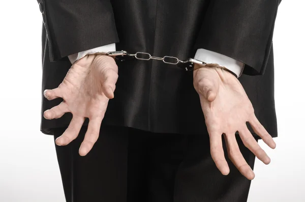 Corruptie en omkoping thema: zakenman in een zwart pak met handboeien op zijn handen op een witte achtergrond in studio geïsoleerd — Stockfoto
