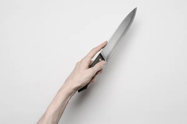 Тема убийства и Хэллоуина: рука мужчины тянется за ножом, человеческая рука держит нож изолированный на сером фоне в студии сверху — стоковое фото