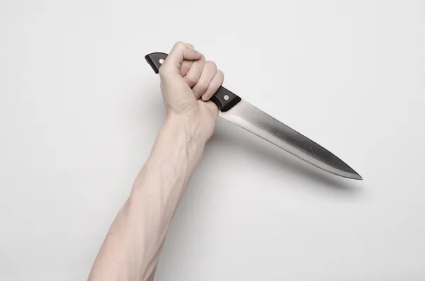 Murder and Halloween theme: A man's hand reaching for a knife, a human hand holding a knife isolated on a gray background in studio from above — Stock Photo, Image