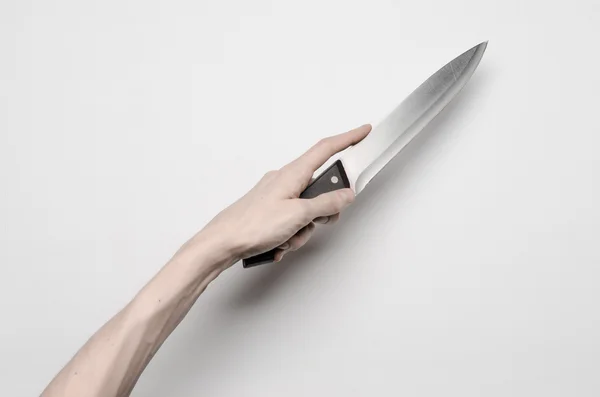 Mord och Halloween tema: en mans hand att nå för en kniv, en mänsklig hand håller en kniv isolerad på en grå bakgrund i studio från ovan — Stockfoto